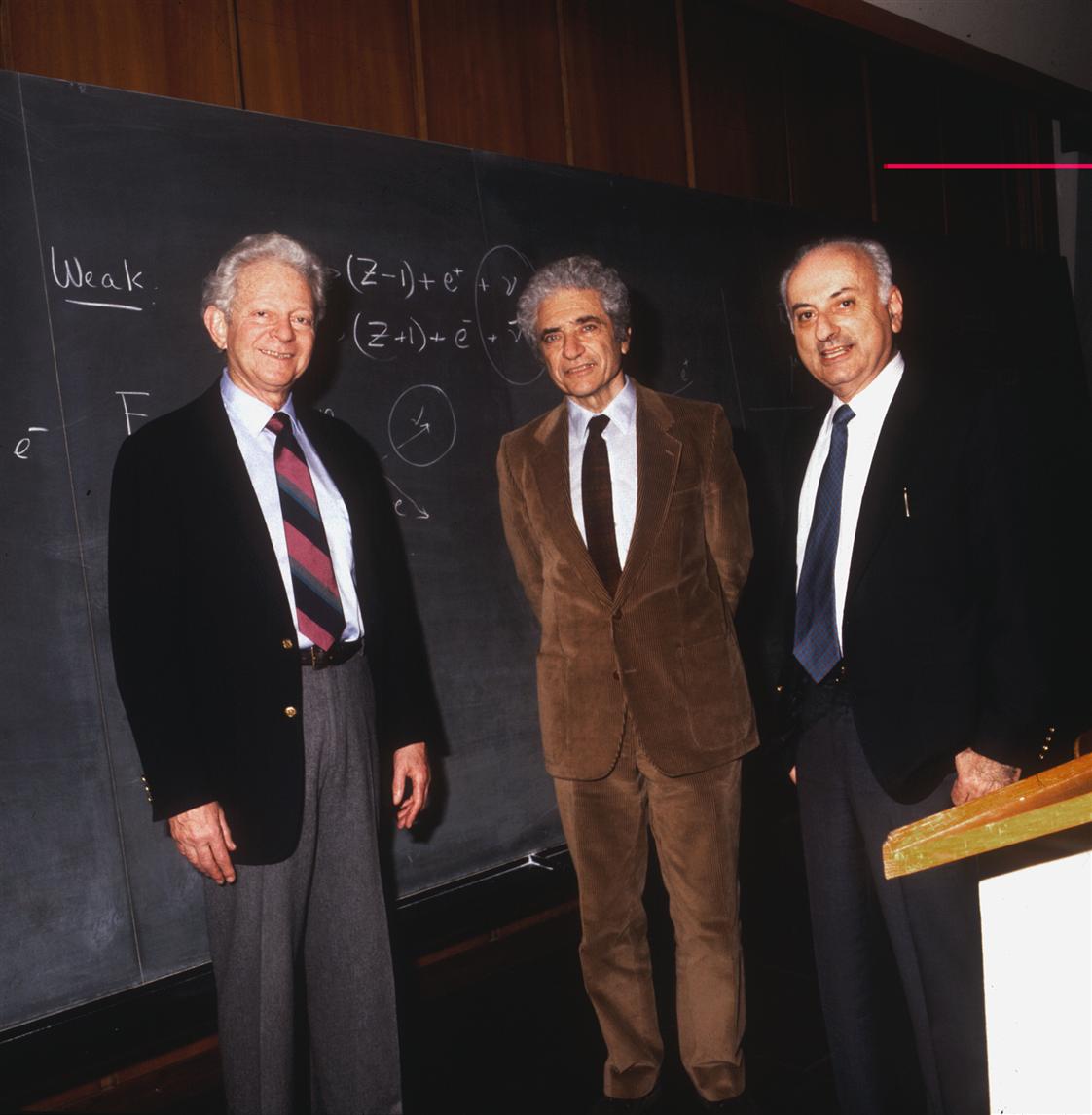 Three scientists posing in front of a blackboard