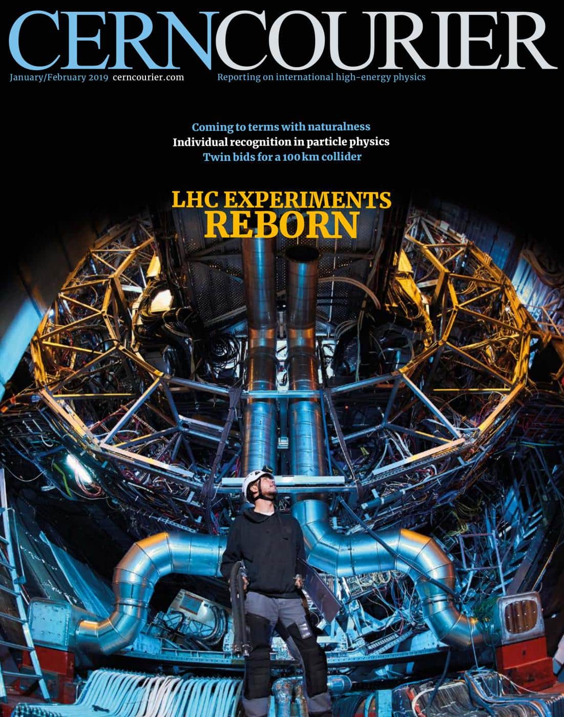 The cover of the January-February 2019 edition of the CERN Courier, showing a person wearing a white hardhat standing in front of a giant piece of scientific equipment with several blueish pipes visible