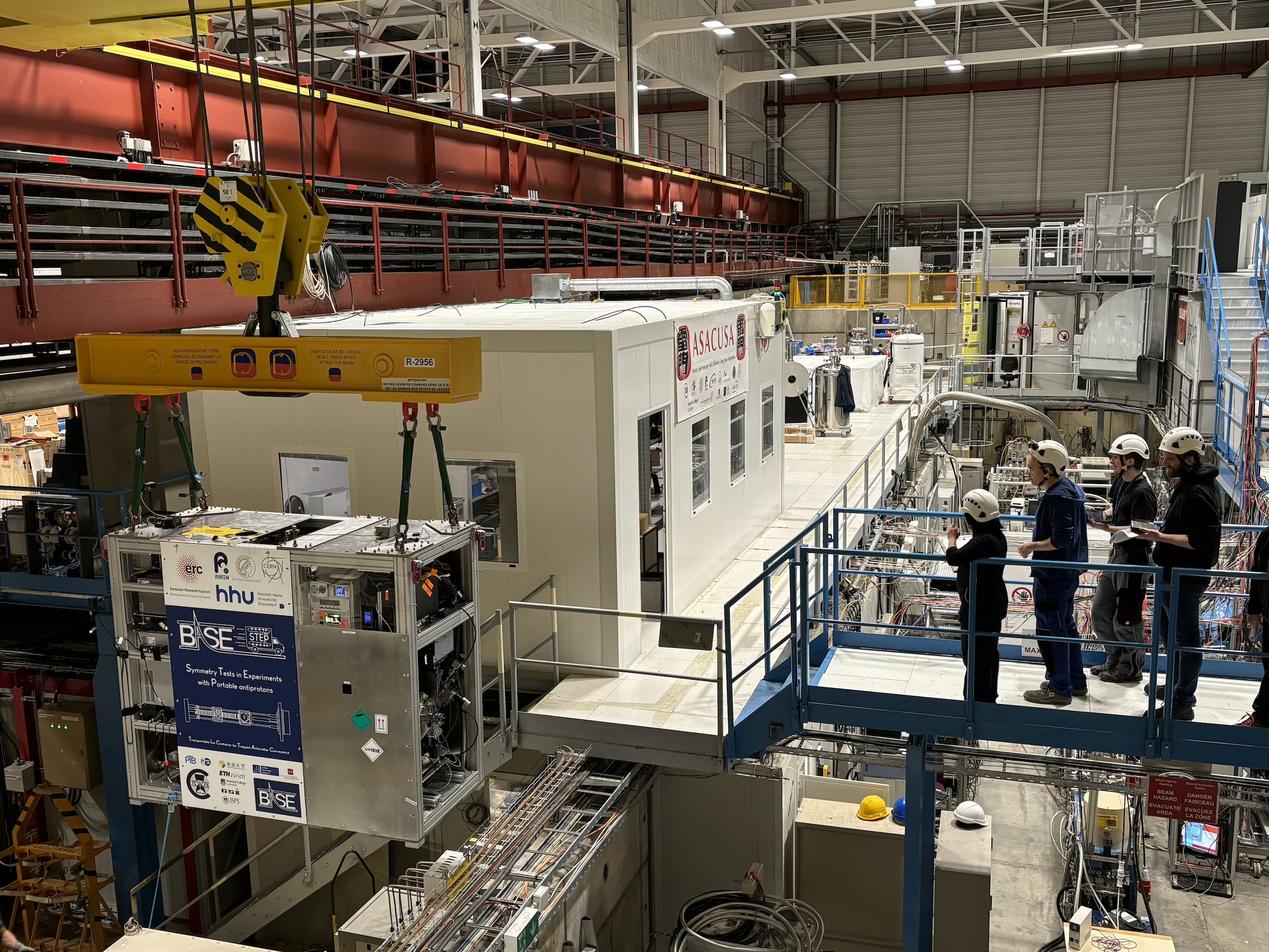 experiment hall with blocks of concrete and a team looking at a metallic frame being lifted.