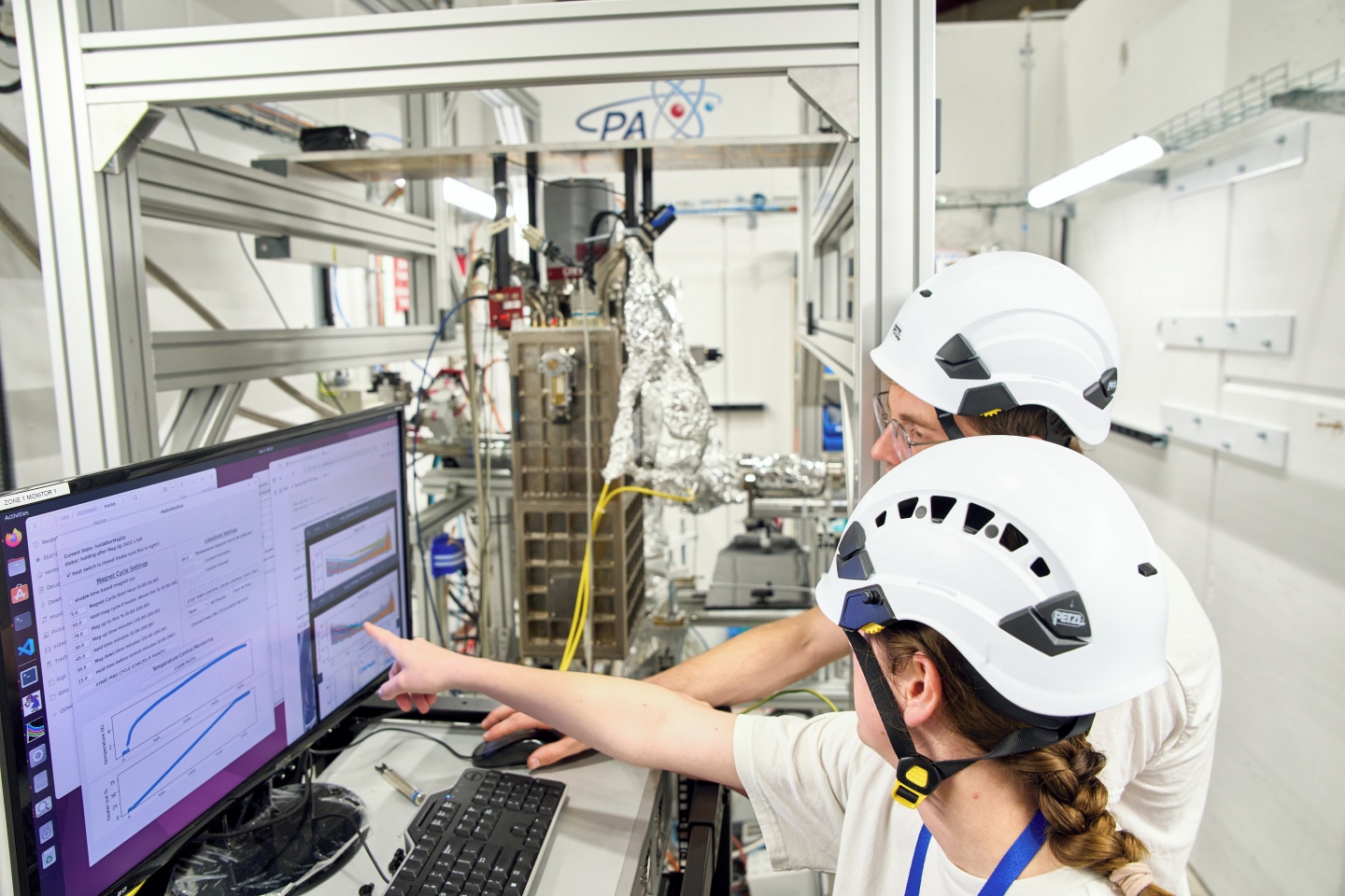 A woman and a man scientist look at a screen with graphs
