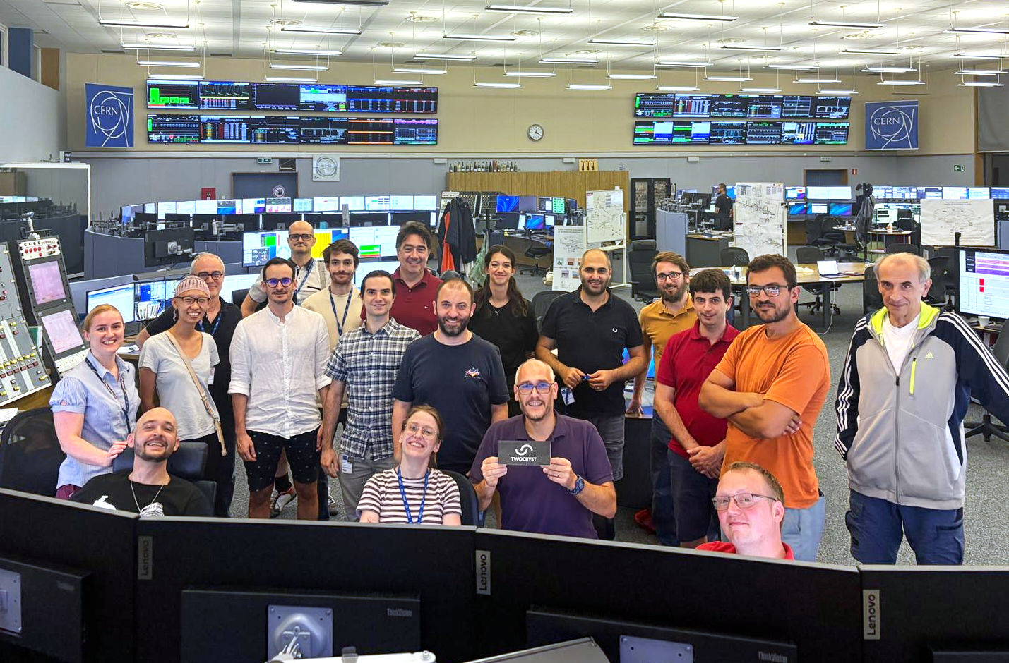 A group of people smiling at the camera and surrounded by many monitors.