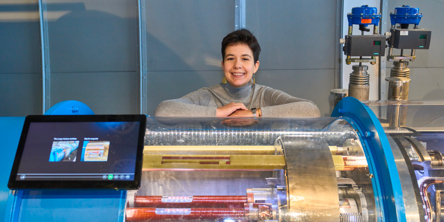 Alicia, PhD student, portrayed behind a model of a LHC magnet 