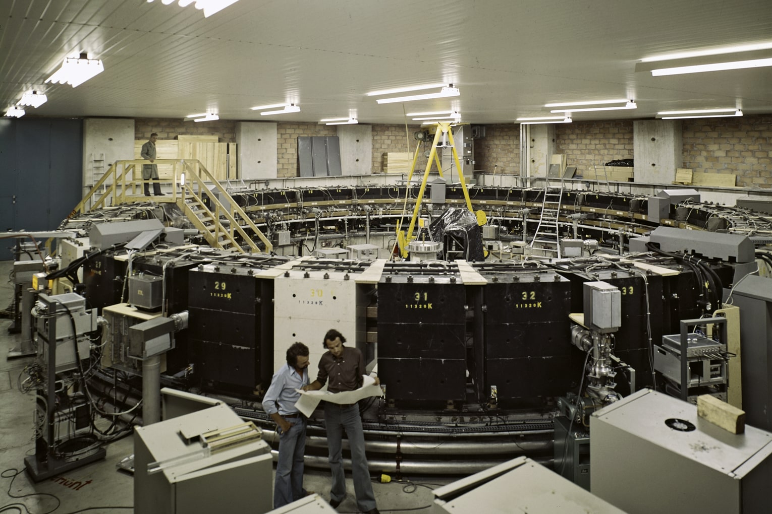 Two men standing infront of a large ring of equipment